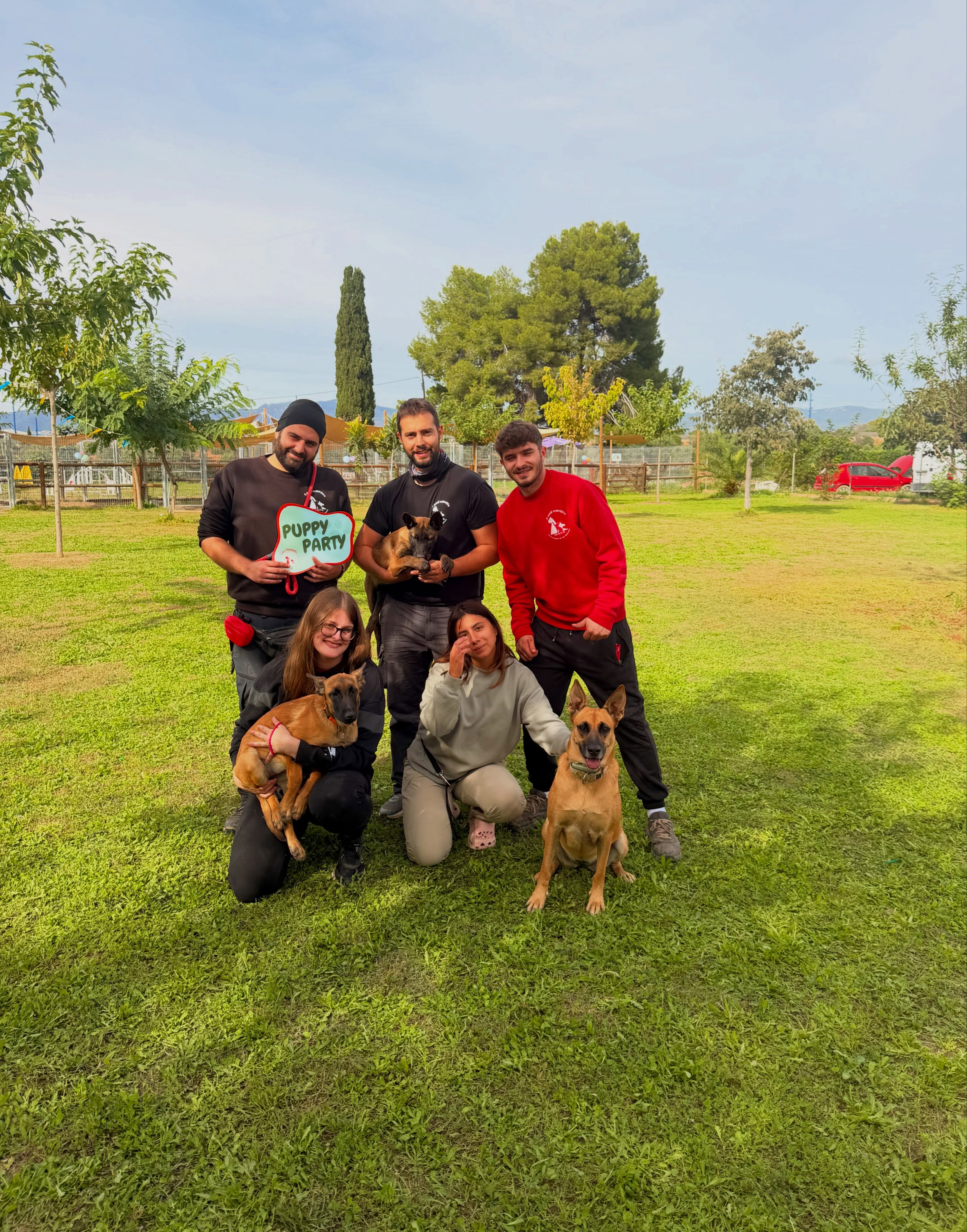 Photo de groupe avec cinq personnes et trois chiens sur la pelouse de Can Penedès.